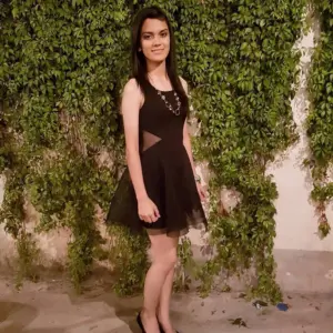 Zapatos de tacón medio brillante negro combinados con vestido formal en fiesta nocturna al aire libre.